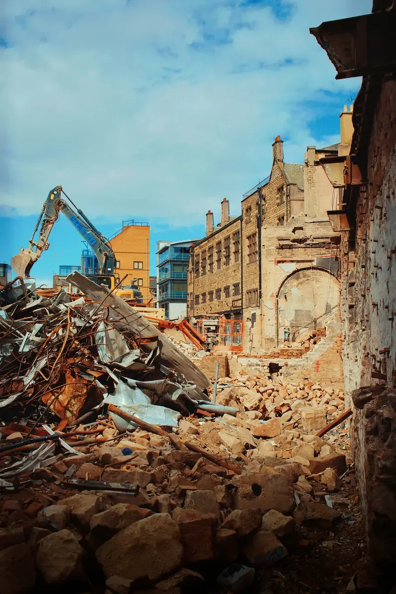 A masonry building coming down at the edge of a street, rubble across the frontage